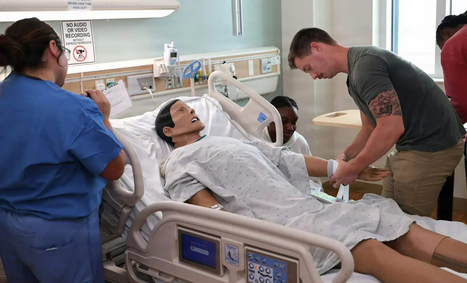 Healthcare professionals practicing clinical skills with a medical training mannequin